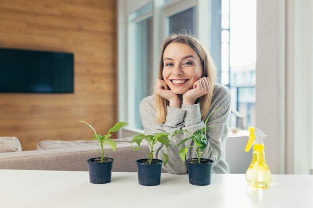 vrouw thuis zorgt voor bloempotten schenkt bloemen zittend aan tafel