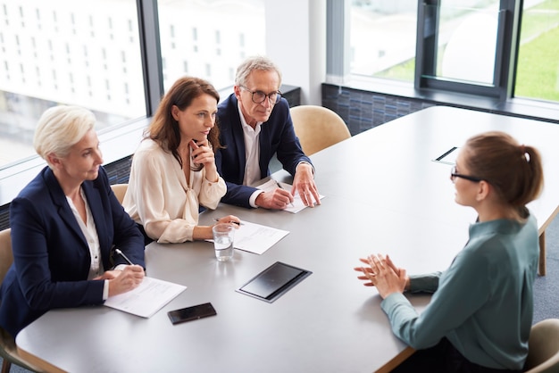 Vrouw tijdens sollicitatiegesprek en drie elegante directieleden