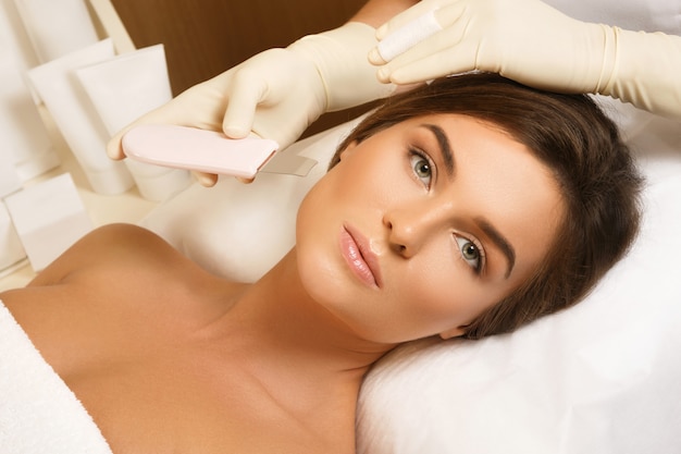 Vrouw tijdens ultrasone gezichtsreinigingsprocedure