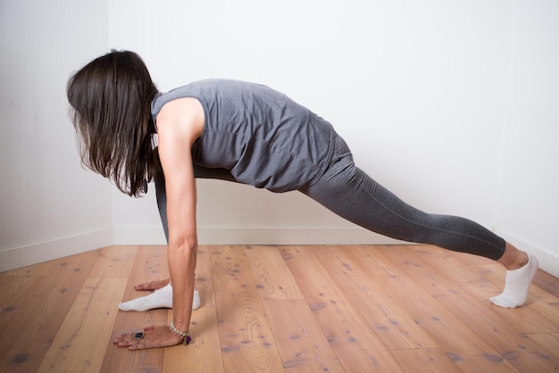 Foto vrouw tijdens yoga oefening thuis gekleed in grijs lage lunge pose witte achtergrond verkeerde positie