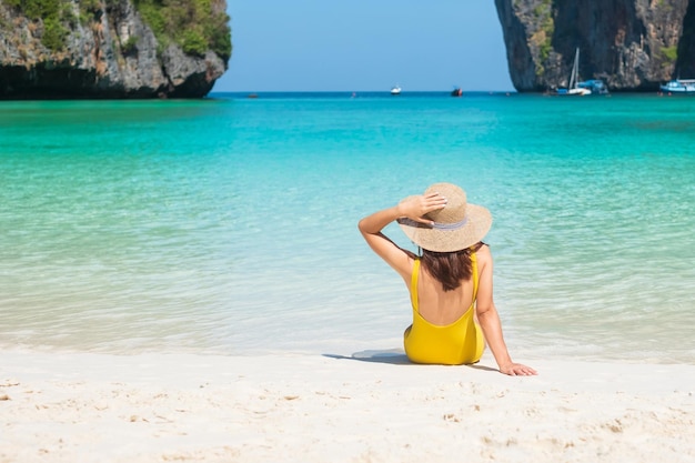 Vrouw toerist in gele zwembroek en hoed gelukkige reiziger zonnebaden op Maya Bay strand op Phi Phi eiland Krabi Thailand landmark bestemming Zuidoost-Azië reizen vakantie en vakantie concept