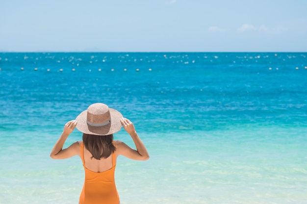 Foto vrouw toerist in oranje badpak en hoed gelukkige reiziger zonnebaden op paradise beach op eilanden bestemming reislust azië reizen tropische zomervakantie en vakantieconcept