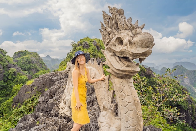 Vrouw toerist op achtergrond van verbazingwekkende enorme draak standbeeld op kalkstenen bergtop in de buurt van hang mua