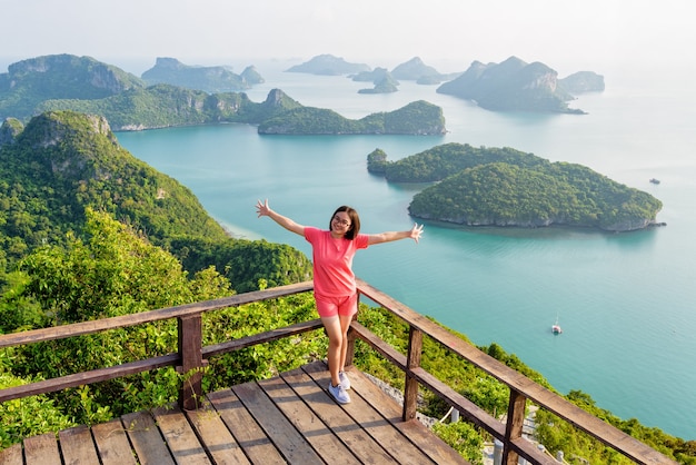 Vrouw toeristische staande poseren op het podium is piek uitzichtpunt van ko wua ta lap en prachtige natuur landschap van eiland en zee in mu ko ang thong national marine park, surat thani, thailand