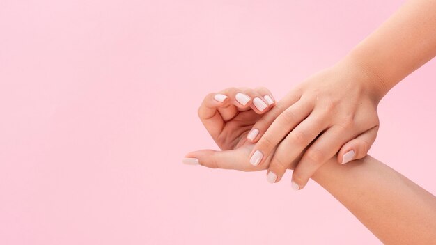 Vrouw toont haar manicure op roze achtergrond met kopie ruimte