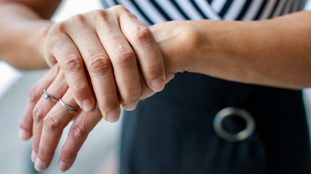 Vrouw toont hand en houdt handpalm vast met pijn, lijden, pijn en tintelingen. Concept van Guillain-barre-syndroom en gevoelloos effect van de handenziekte.