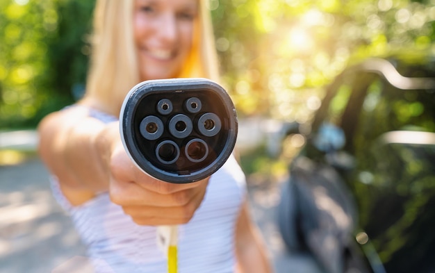 Vrouw toont Type 2 plug-oplaadkabel voor elektrische auto of EV-auto om op te laden. Milieuvriendelijk alternatief energieconcept