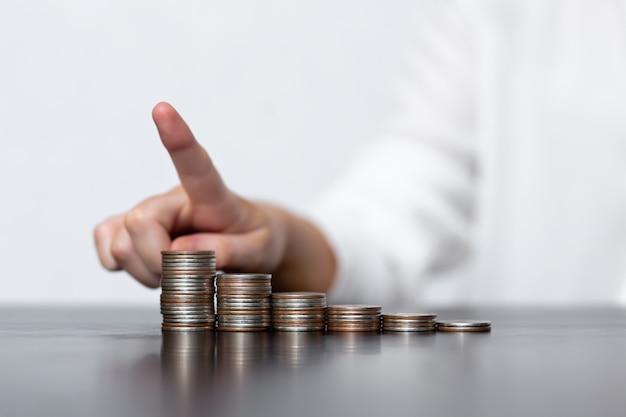 Vrouw toont winstgroei en geld munten in stapels op een zwarte tafel. Het concept van geld besparen, financiën en investeringsbeleid.