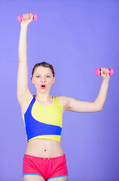 Vrouw trainen met dumbbells Fitness oefeningen met dumbbells Training met dumbbells Meisje houdt roze dumbbells Biceps oefeningen voor vrouw Gezond leven gezond levensstijl concept