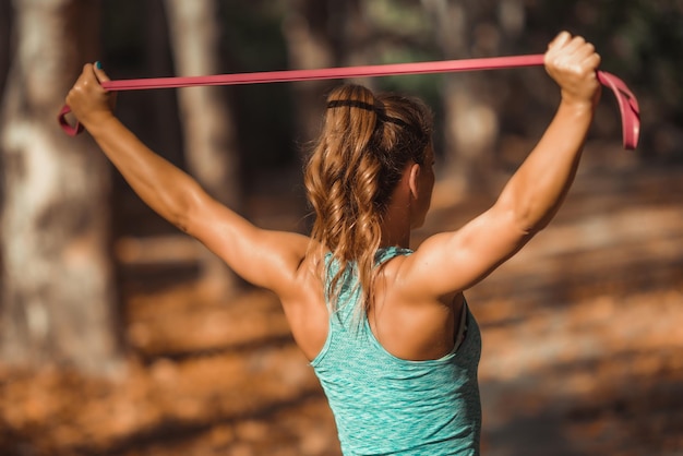 Foto vrouw trainen met elastische band buitenshuis in de herfst