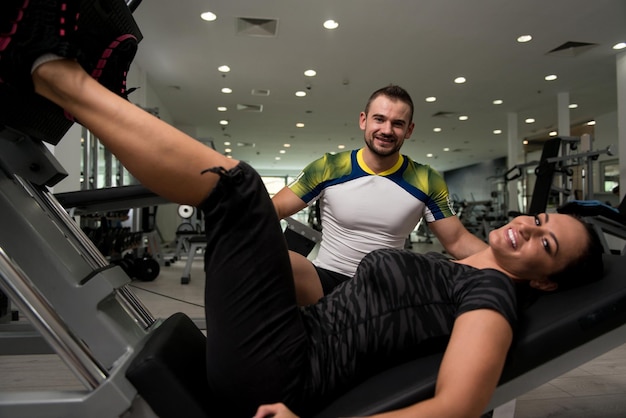 Vrouw traint benen op machine met personal trainer