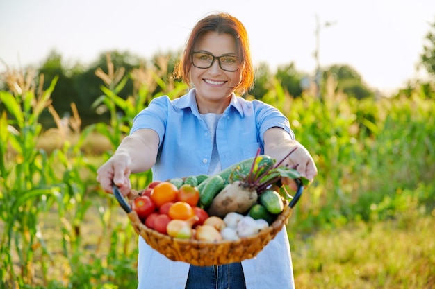 Vrouw tuinman boer van middelbare leeftijd met mand met rijpe groenten