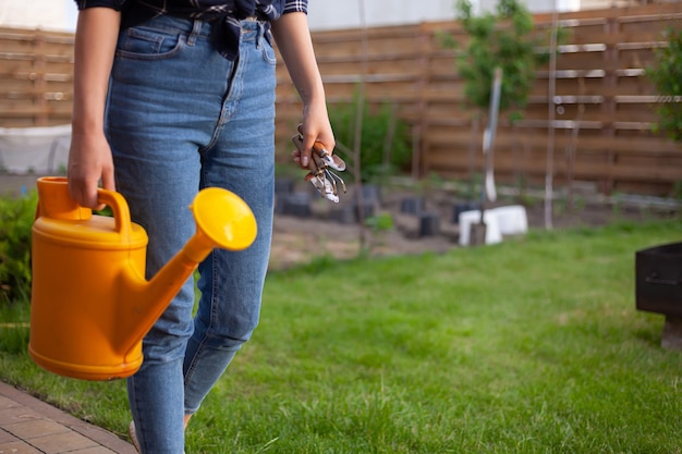 Vrouw tuinman in hoed planten water geven in de tuin in de achtertuin