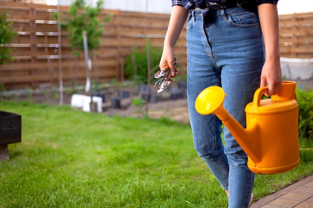 Vrouw tuinman in hoed planten water geven in de tuin in de achtertuin