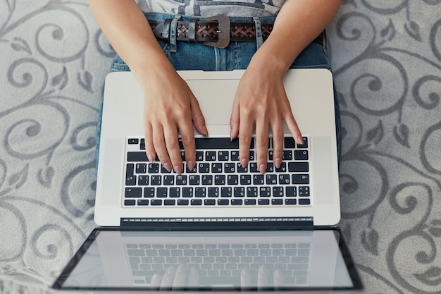 Vrouw typen op laptop en zittend op de vloer