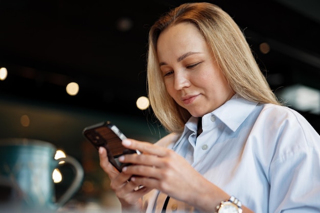 Vrouw typt tekstbericht op smartphone terwijl ze in een café zit