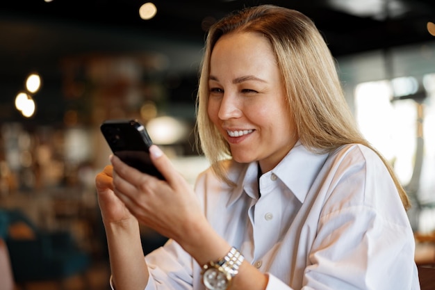 Vrouw typt tekstbericht op smartphone terwijl ze in een café zit