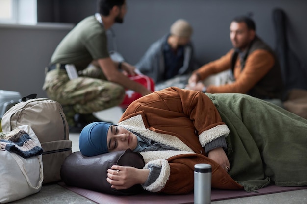 Foto vrouw uit het midden-oosten slaapt op de vloer in een vluchtelingenopvangcentrum