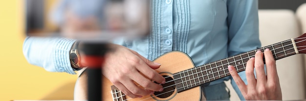 Vrouw ukulele spelen en filmen telefoon close-up muziek blogger concept