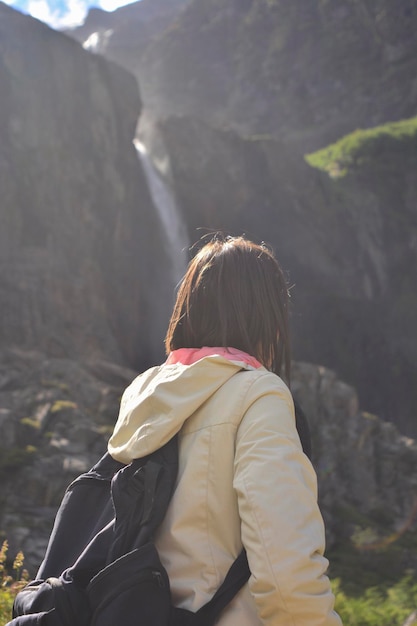 vrouw van achteren met een witte jas die naar een grote waterval kijkt in de tronador vulkaan bij Bariloche