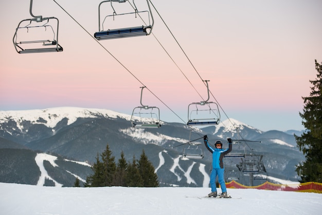 Vrouw van de skiër hief omhoog stokken bij de skitoevlucht op