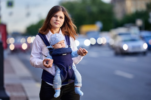 Vrouw van jaar oud met baby in draagdoek loopt in de buurt van verkeer