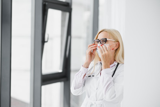 Vrouw van middelbare leeftijd die doktersuniform draagt in de kliniek