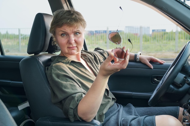 Foto vrouw van middelbare leeftijd die een auto bestuurt, uit haar ontevredenheid