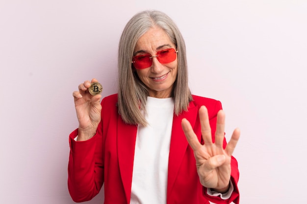 Vrouw van middelbare leeftijd die lacht en er vriendelijk uitziet met nummer vier bitcoin-concept
