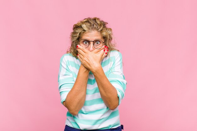 Foto vrouw van middelbare leeftijd die mond bedekt met handen met een geschokte, verbaasde uitdrukking, een geheim bewaren of oeps zeggen