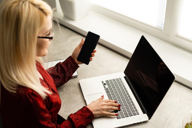 Vrouw van middelbare leeftijd die thuis op laptop werkt