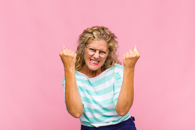 Vrouw van middelbare leeftijd die triomfantelijk schreeuwt, lacht en zich blij en opgewonden voelt terwijl ze succes viert