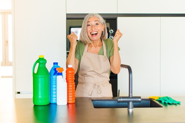 Vrouw van middelbare leeftijd die zich blij, verrast en trots voelt, schreeuwt en succes viert met een grote glimlach