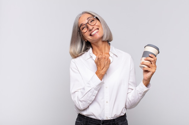 Vrouw van middelbare leeftijd die zich gelukkig, positief en succesvol voelt, gemotiveerd wanneer ze voor een uitdaging staat of het koffieconcept met goede resultaten viert