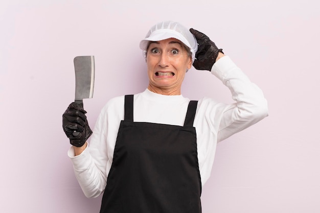 Vrouw van middelbare leeftijd die zich gestrest, angstig of bang voelt met het concept van de slager met handen op het hoofd