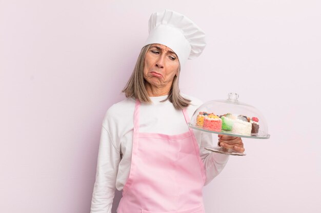 Foto vrouw van middelbare leeftijd die zich verdrietig en zeurderig voelt met een ongelukkige blik en een huilend bakker- en gebakconcept