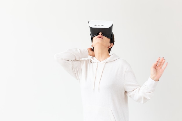 Vrouw van middelbare leeftijd in een witte trui kijken naar een film met een bril van virtual reality