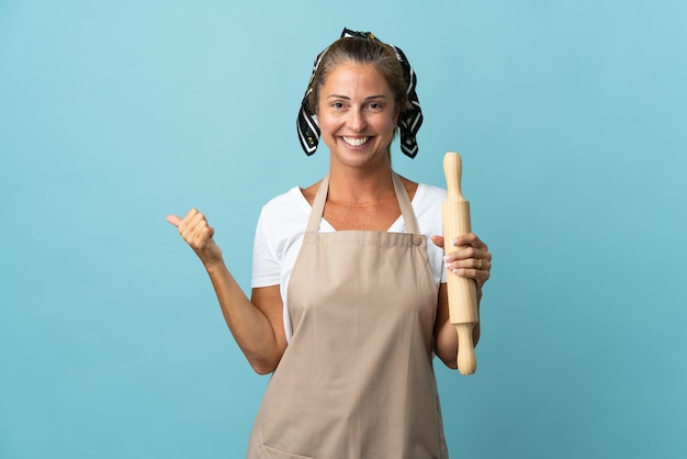 Vrouw van middelbare leeftijd in eenvormige chef-kok die naar de kant wijst om een product te presenteren