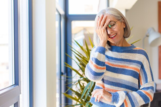 Vrouw van middelbare leeftijd lacht en slaat voorhoofd, zoals oh zeggen! ik was het vergeten of dat was een domme fout