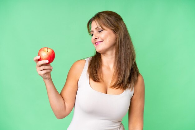 Vrouw van middelbare leeftijd met een appel over geïsoleerde achtergrond met gelukkige uitdrukking