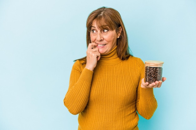 Vrouw van middelbare leeftijd met een koffiepot geïsoleerd op blauwe achtergrond