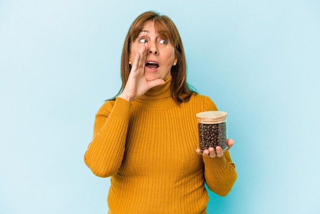 Vrouw van middelbare leeftijd met een koffiepot geïsoleerd op blauwe achtergrond