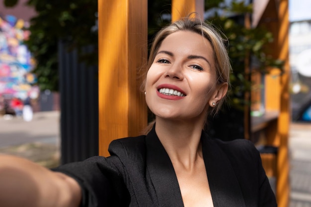 Vrouw van middelbare leeftijd neemt overdag een selfie in de zonnestralen in de stad