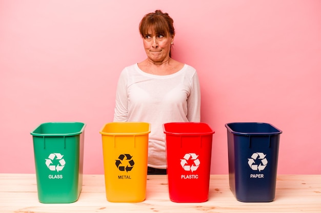 Vrouw van middelbare leeftijd recycling geïsoleerd op roze achtergrond verward voelt twijfelachtig en onzeker