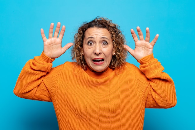 Foto vrouw van middelbare leeftijd schreeuwt in paniek of woede, geschokt, doodsbang of woedend, met de handen naast het hoofd