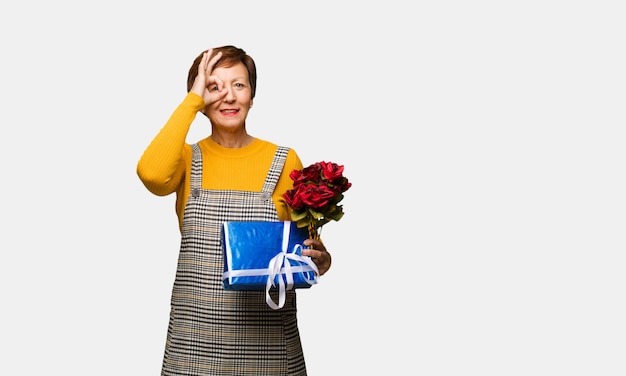 Vrouw van middelbare leeftijd vieren Valentijnsdag vertrouwen doen ok gebaar op oog