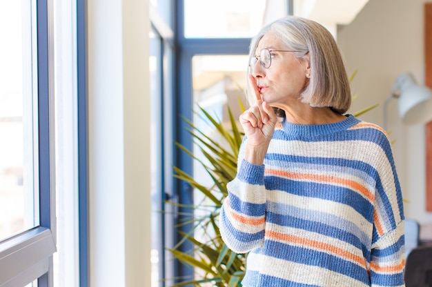 Vrouw van middelbare leeftijd vraagt om stilte en stilte, gebaart met de vinger voor de mond, zegt shh of houdt een geheim