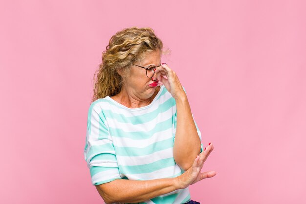 Vrouw van middelbare leeftijd walgt en houdt neus vast om te voorkomen dat ze een vieze en onaangename stank ruikt