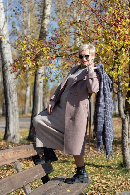 Vrouw van middelbare leeftijd zit in de herfst op een bankje in het park. Hoge kwaliteit foto