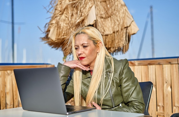 Vrouw van middelbare leeftijd zitten met behulp van laptop